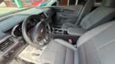 Front interior of a Chevrolet car showing gray cloth seats, steering wheel with Chevrolet emblem, center console, and dashboard view