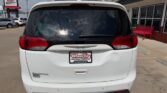 Rear view of a white minivan parked in a dealership lot, with a Wheel City Auto Finance Centers license frame on the bumper.