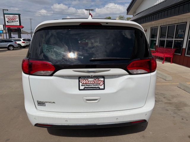 Rear view of a white minivan parked in a dealership lot, with a Wheel City Auto Finance Centers license frame on the bumper.