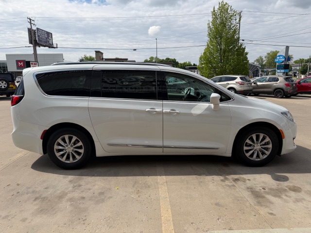 Side view of a white minivan parked in a parking lot, with tinted windows and sliding doors along the side.