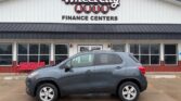 Gray SUV parked in front of Wheel City Auto Finance Centers storefront with red benches nearby in a dealership lot.