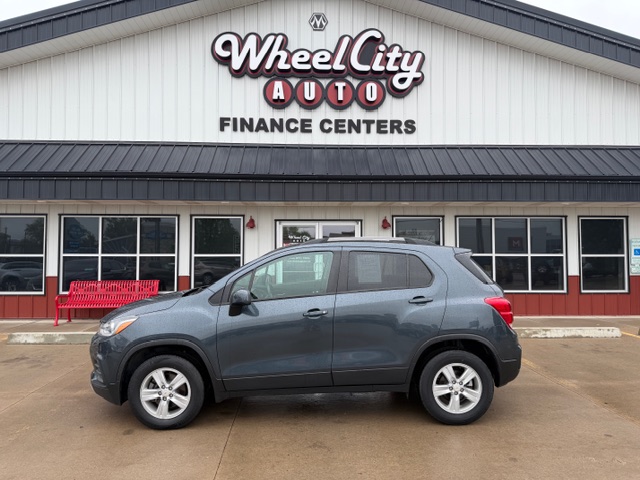 Gray SUV parked in front of Wheel City Auto Finance Centers storefront with red benches nearby in a dealership lot.
