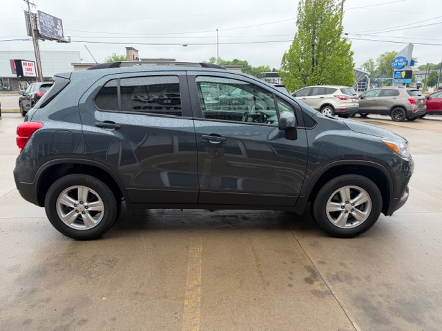 Gray SUV parked in a wet parking lot, shown in side profile, with other cars in the background.