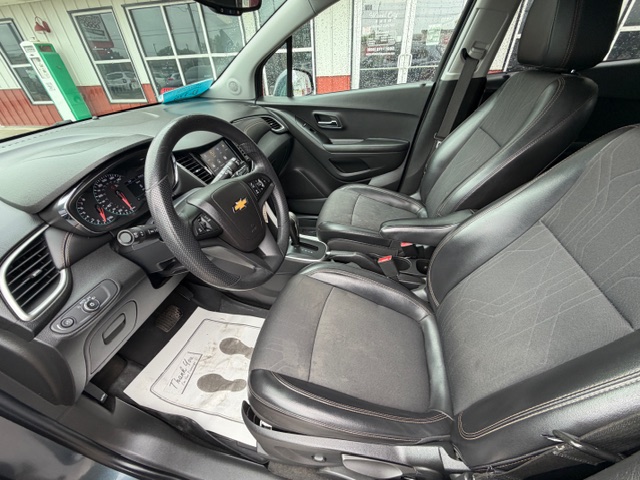 Front interior of a Chevrolet SUV showing black leather seats, steering wheel with Chevrolet emblem, dashboard, and center console.