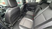 Interior view of a black leather back seat in a car, showing spacious rear seating, seat belts, and front seats with the driver's area visible on the left.