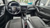 Interior of a Chevrolet car: view of the driver's area with steering wheel, center touchscreen, gear shifter, and black leather seats