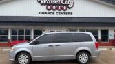 Silver minivan parked in front of Wheel City Auto Finance Centers storefront with a white exterior and large windows.