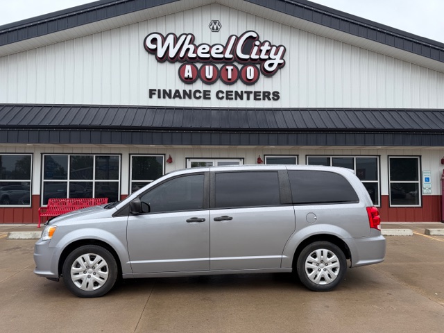 Silver minivan parked in front of Wheel City Auto Finance Centers storefront with a white exterior and large windows.