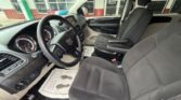 Front interior of a left-hand-drive pickup with black fabric seats, steering wheel, dashboard, and front passenger seat; dealership storefront visible through the windows.