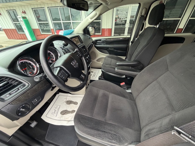 Front interior of a left-hand-drive pickup with black fabric seats, steering wheel, dashboard, and front passenger seat; dealership storefront visible through the windows.