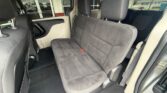 Interior of a gray fabric bench seat in a vehicle, showing headrests, door panel, and floor mats from the rear passenger side.