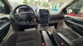 Front interior of a black SUV, steering wheel with Dodge emblem, center touchscreen and climate controls, cloth seats