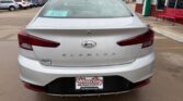 Rear view of a silver Hyundai Elantra in a dealership lot on a rainy day, showing the ELANTRA badge and dealership license plate frame.