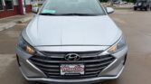 Front view of a silver Hyundai sedan in a dealership lot on a rainy day; dealership plate reads Wheel City Auto Finance Centers.