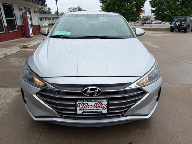 Front view of a silver Hyundai sedan in a dealership lot on a rainy day; dealership plate reads Wheel City Auto Finance Centers.