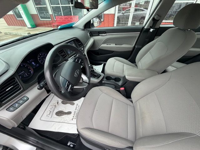 Front interior of a gray Hyundai sedan with cloth seats, steering wheel, dashboard, and center console visible from the passenger side