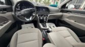 Inside a Hyundai car: driver and passenger seats with gray upholstery, steering wheel, and the center console with a touchscreen display.