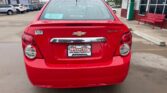 Rear view of a red Chevrolet car with Wheel City license plate frame in a dealership lot. Rain on the rear window and taillights visible.