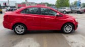 Side view of a red four-door sedan parked in a car lot.