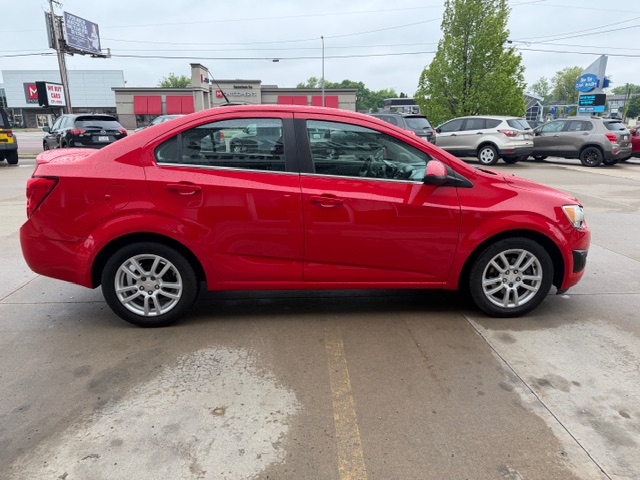 Side view of a red four-door sedan parked in a car lot.