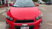 Front view of a red Chevrolet car at a dealership, showing a Wheel City Auto Finance plate on the bumper.