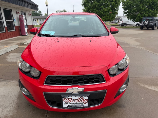 Front view of a red Chevrolet car at a dealership, showing a Wheel City Auto Finance plate on the bumper.