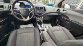 Front interior of a Chevrolet car, viewed from the back seat, showing the steering wheel, center console, and two front seats.