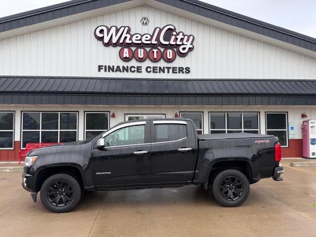 Black four-door pickup truck parked in front of Wheel City Auto Finance Centers storefront.