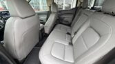 Interior of a car showing gray leather rear seats with headrests and matching floor mats viewed from the side door.
