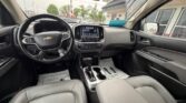 Interior of a Chevrolet SUV showing the steering wheel, center touchscreen, and gray seats.