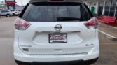 Rear view of a white Nissan Rogue SL AWD parked at a dealership, with a Wheel City license plate frame on the bumper.