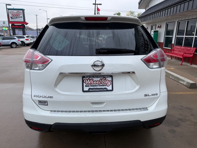 Rear view of a white Nissan Rogue SL AWD parked at a dealership, with a Wheel City license plate frame on the bumper.