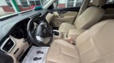 Front interior of a beige leather SUV showing driver's seat, steering wheel, and center console.