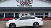White sedan parked in front of the Wheel City Auto Finance Centers storefront.