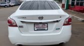 Rear view of a white Nissan Altima S in a dealership lot, raindrops on the rear window; dealer plate reads Wheel City Auto Finance Centers.