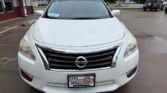 Front view of a white Nissan sedan parked in a dealership lot, with a Wheel City Auto Finance Centers license plate frame on the bumper.