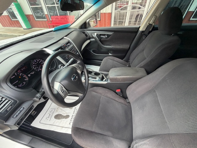 Interior view of a gray fabric-seat car from the driver’s side, showing the steering wheel, dashboard, center console, and front seats in a parked vehicle