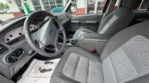 Front interior of a gray Ford pickup, showing the steering wheel, dashboard, center console, and two front seats from the driver's side.