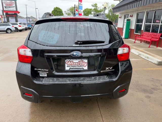 Rear view of a black Subaru XV Crosstrek at a car dealership lot, with Wheel City Auto Finance Centers license plate frame and a wet rear window.