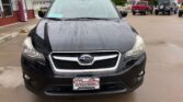 Front view of a black Subaru SUV parked in a dealership lot on a rainy day, with water droplets on the hood and windshield; car has Wheel City Auto Finance Centers plate frame.