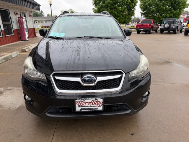 Front view of a black Subaru SUV parked in a dealership lot on a rainy day, with water droplets on the hood and windshield; car has Wheel City Auto Finance Centers plate frame.