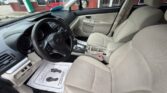 Front interior of a beige SUV showing steering wheel, driver and passenger seats, center console, and a dealership exterior visible through the windows.