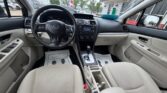 Inside view of a light beige car interior: steering wheel, dashboard, gear shifter, and front seats from the back seat perspective.