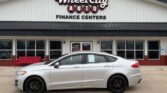 White sedan parked in front of Wheel City Auto Finance Centers storefront.