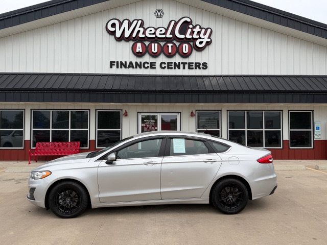 White sedan parked in front of Wheel City Auto Finance Centers storefront.