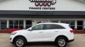 White SUV parked in front of the Wheel City Auto Finance Centers dealership storefront.
