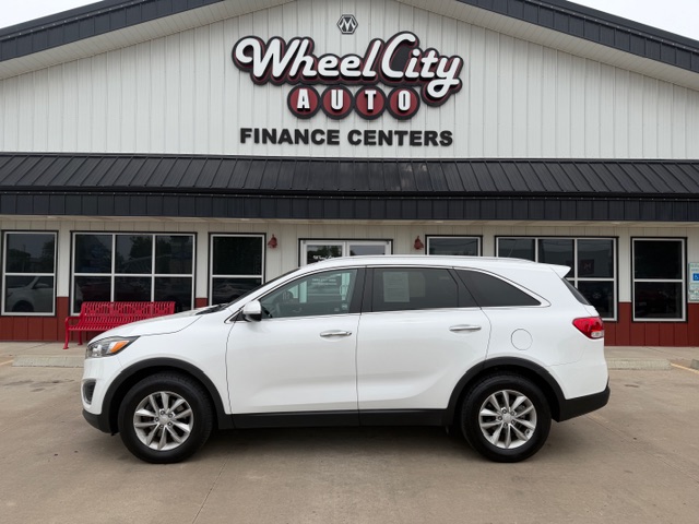 White SUV parked in front of the Wheel City Auto Finance Centers dealership storefront.