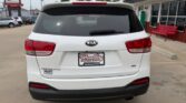 White Kia SUV rear view at a car dealership, with a Wheel City license plate frame visible on a cloudy day.
