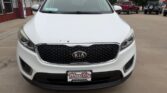 Front view of a white Kia SUV parked in a car dealership lot with Wheel City Auto Finance Centers license plate frame on the bumper.