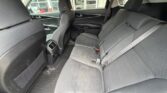 Interior of a mid-size car showing the back seats in gray fabric with center armrest folded up and visible seatbelts.